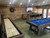Plank & Hide Co Plank & Hide Isaac Slate Pool Table, featuring a blue felt surface with pool balls racked, in a game room with wooden wall paneling and a mounted TV.
