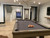Plank & Hide Co Plank & Hide Isaac Slate Pool Table with balls arranged on the surface, in a modern recreational room with white brick wall, wooden flooring, and contemporary lighting fixtures.