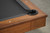 Doc & Holliday Scholar Slate Pool Table, close-up of corner showing wooden frame and black rubber cushion detail.