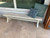 Sawyer Twain Metro All Weather Outdoor Pool Table with Storage Drawer, modern white pool table placed on a patio with cushions against the window.