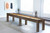 Brunswick Billiards Brunswick Soho Shuffleboard Table, a rustic wooden shuffleboard game table placed in a modern, minimalistic room with large windows and abstract art on the wall.