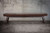 Doc & Holliday George Shuffleboard Table by Doc & Holliday, antique coffee wood finish, modern design with glass top, set against concrete wall background.