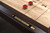 Doc & Holliday George Shuffleboard Table by Doc & Holliday, close-up of a vintage shuffleboard scoring system with gold-colored numbered tiles on a dark wood surface.