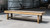 Doc & Holliday Hank Shuffleboard Table, American Chocolate, outdoor view of a long wooden shuffleboard table with a smooth playing surface, sturdy wooden supports, and a rustic setting.