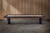 Doc & Holliday Savant Shuffleboard Table by Doc & Holliday in Brown Sugar Finish, sleek hardwood surface with black legs, in a modern indoor setting with wooden wall background.