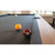 American Heritage Billiards Abbey Slate Pool Table in Antique Grey, close-up of billiard balls (yellow and 7) on the black felt surface with natural light from windows in the background.