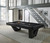American Heritage Billiards Annex Pool Table, black ash finish, modern design in a spacious game room with large windows and contemporary decor.