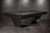 Doc & Holliday TRON Steel Slate Pool Table, modern pool table with black finish and sleek legs, set against a concrete wall background.
