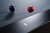 Doc & Holliday TRON Pool Table in Steel Grey, close-up of the table's textured black surface with two billiard balls, purple and red, and a metallic logo on the edge of the table.