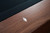 Doc & Holliday TRON Steel & Slate Pool Table in Walnut, close-up image showing the polished walnut wood surface with a mother-of-pearl inlay detail on the table.