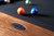 Doc & Holliday Muse Pool Table, close-up of the wooden corner with the branded metal plate and pool balls on the felt surface.