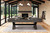 American Heritage Billiards American Heritage Halifax 8' Slate Pool Table, Charcoal Finish, in a modern sunroom with large windows, stone fireplace, and wooden ceiling.