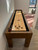 Brunswick Billiards Brunswick Parsons Pool Table & Shuffleboard Combo, a wooden shuffleboard table with a digital score display and smooth surface, located in a modern room with large windows and seating area.