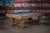Doc & Holliday Hank Slate Pool Table, rustic silver brown oak with a slate playing surface against a distressed American flag-themed metal wall.