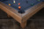 Doc & Holliday Hank Slate Pool Table | Rustic Silver Brown Oak, close-up view of the corner with wood frame and billiard balls on the blue felt surface.