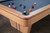 Close-up of the Preakness pool table corner showing walnut inlay racing stripe detail in the maple apron, smooth rounded rail edge, mother-of-pearl diamond sight, and precision joinery. A showcase of Doc & Holliday’s fine woodworking.