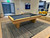Doc & Holliday Preakness Pool Table in Maple, sleek wooden pool table with dark felt surface, four pool cues, in a modern recreational room.