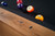 Doc & Holliday Parsons Pool Table in Rustic White Oak, close-up of the wooden frame with natural wood grain and finish, featuring a black felt playing surface and billiard balls.
