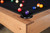 Doc & Holliday Parsons Pool Table in Rustic White Oak, close-up of corner with playing balls on black felt surface and wooden edge.
