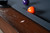 Doc & Holliday Caroline Slate Pool Table, close-up of the wooden edge with slate surface and billiard balls in the background.