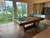 Doc & Holliday Kaci Slate Pool Table in Grey Walnut, pool table with cues in a room with large windows and outdoor view.