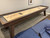 Doc & Holliday George Shuffleboard Table | Gray Walnut, modern shuffleboard table with wooden finish, rectangular playing surface, and adjustable legs in a game room.