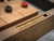 Doc & Holliday Hank Shuffleboard in Rustic Silver Brown Oak Finish, close-up of the shuffleboard table with gold scoring tiles embedded in the wooden edge.