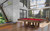 Plank & Hide Covington Slate Pool Table | Free Install, a stylish pool table with a red felt surface and wooden frame situated in a modern, glass-enclosed room with panoramic views of a lush outdoor landscape.