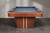 Doc & Holliday Preakness Slate Pool Table in Walnut & Maple, a stylish billiards table featuring a sleek blue felt surface, wooden frame, and unique tapered wooden legs.