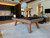 Doc & Holliday George Pool Table & Shuffleboard Combo in Gray Walnut, wooden pool table with black playing surface, shuffleboard setup, modern indoor lounge setting with living area, plants, and decorative elements.