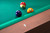 Doc & Holliday Paula Parsons Pool Table in Gray Walnut, close-up of billiard balls on green felt surface with wooden edge.