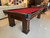 Close-up angle of the Brunswick Oakland Pool Table showcasing espresso wood grain, pedestal legs, and leather drop pockets with braided accents | Sawyer Twain.