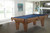 Brunswick Billiards Brunswick Allenton Slate Pool Table in Rustic Dark Brown, indoor setting, large windows, modern decor, with a blue felt surface and detailed craftsmanship.