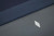 Doc & Holliday Bellano Slate Pool Table by Doc & Holliday in Matte Smoke, close-up of the sleek slate surface showing the textured blue felt and smooth grey finish with a small, illuminated logo.