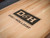 Doc & Holliday Paula Parsons Shuffleboard Table – Natural Walnut, close-up of the table surface with local branding logo.