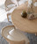 Hooker Furniture Retreat Pole Rattan Round Light Wood Dining Table with 1-20 inch leaf, shown with elegant decorative vases and coral accents in a modern dining room setting.
