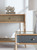 Hooker Furniture Retreat Pole Rattan Bedside Table in Blue, showcasing a stylish rattan drawer with wooden frame and natural wood accents in a modern bedroom setting.