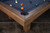 Detail view of the Doc & Holliday Hank pool table in distressed Rustic Silver Brown Oak, highlighting finger-jointed rails and leather drop pocket