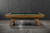 Doc & Holliday George Slate Pool Table by Doc & Holliday in Glazed Maple, with green felt surface and wooden frame in front of a dark textured wall.