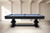 Environmental photo shoot of the Sawyer Twain Exclusive Beaumont pool table in Black Ash, shown in a bright interior with Academy Blue felt, solid ash wood rails, pedestal legs, and true 3-piece slate construction.