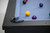 Close-up of the Beaumont Black Ash slate pool table with a genuine leather corner pocket, Championship Academy Blue felt, solid ash wood rail, and Doc & Holliday luxury billiard balls.