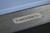 Plank & Hide Co Beaumont Slate Pool Table, close-up of the engraved metal logo on a dark ash wooden surface.