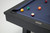 Plank & Hide Co Isaac Slate Pool Table in Black Ash, detailed close-up of the pool table surface with billiard balls scattered on the blue felt and a metal plaque on the frame.