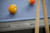 Close-up of the Plank & Hide name plate on the Beaumont slate pool table in Marble Grey, styled with cue sticks and Academy Blue felt for a refined game room look.
