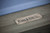 Shallow-focus detail of the Beaumont pool table in Marble Grey, showcasing the Plank & Hide steel name plate.