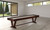 C.L. Bailey Skylar Shuffleboard in Warm Chestnut, modern indoor shuffleboard table with wooden finish in a bright, minimalistic room with large windows.