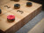 Close-up view of black and red shuffleboard pucks on the maple butcher block playfield of the Doc & Holliday Hank Shuffleboard Table, featuring the recessed scoring system and textured grey carpet lining.