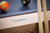Plank & Hide Co Beaumont 8' Slate Pool Table by Plank & Hide – Honey Ash, detail of the wooden frame with metal label, billiard balls, and pool cues.