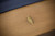 Corner close-up of the Plank & Hide Deco slate pool table showing the golden brass pin stripe, Glazed Maple finish, and modern rail detail.