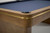 Corner close-up of the Plank & Hide Deco slate pool table showing the golden brass pin stripe and Glazed Maple finish.